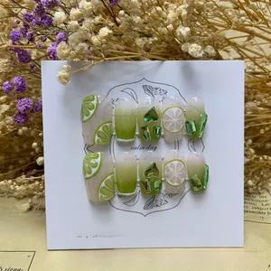 Detail view of handmade press-on nails with 3D lemon slices and green rhinestone accents