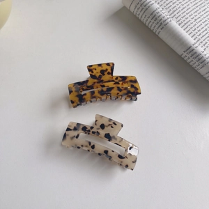 Minimalist acetate hair claws set in tortoiseshell and marble patterns on white surface