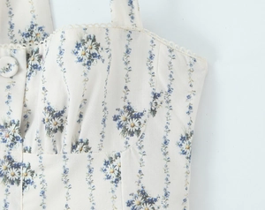 Close-up of blue floral print on off-white dress with lace trim and pleated bust detail
