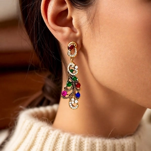 Close-up of vintage gold drop earrings with multi-colored gemstones on a model