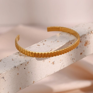 Detail shot of golden open cuff bracelet with vertical wavy texture on stone base
