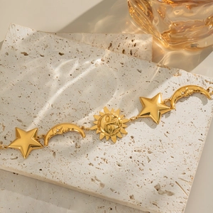 Detail of sun moon and star gold bracelet displayed on stone with elegant light shadows
