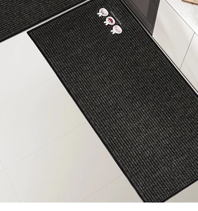 Detail of dark grey striped kitchen mat with cartoon rabbit and functional text on tile