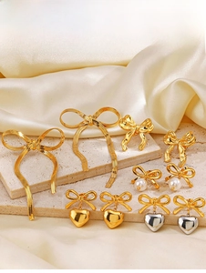 Gros plan de boucles d'oreilles nœuds dorés et pendentifs cœurs sur pierre