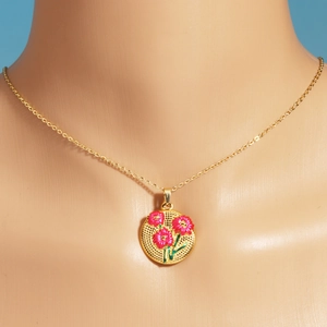 Gros plan du pendentif tulipe doré avec fleurs en émail rose sur chaîne en acier