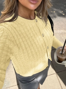 Detailed macro view of the yellow cable knit pattern and metallic buttons on cardigan
