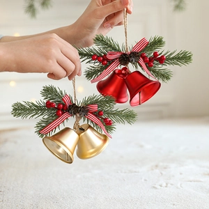 Weihnachtsglocken mit Tannennadeln und Zapfen als festliche Dekoration in der Hand