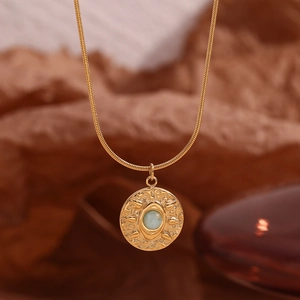 Macro shot of gold hammered coin pendant with blue stone on sleek snake chain