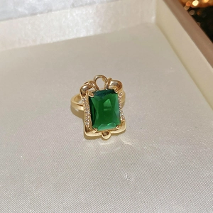 Macro detail of emerald-cut green gemstone ring with gold plating and zircon accents
