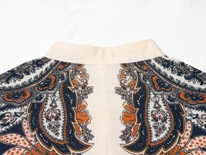 Detail von Stehkragen und Paisley-Print auf beigem gestuftem Kleiderstoff