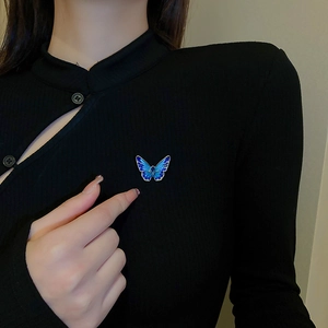 Detail showing blue gradient butterfly brooch with rhinestones on black ribbed clothing