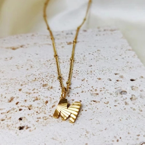 Detailweergave van gouden roestvrijstalen ketting met gestructureerde hanger van letter M