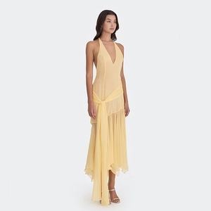 Detail of light yellow halter deep V-neck maxi dress with tie-waist and irregular hemline