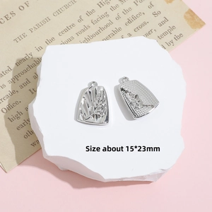 Macro view of silver wheat engraved rectangular pendants on white stone with newspaper