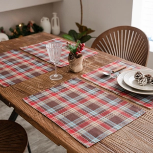 Classic plaid Christmas placemats set on wooden table with holiday table decorations