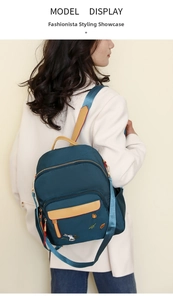 Detail of color-block nylon backpack featuring rabbit embroidery and multiple zip pockets