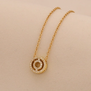 Close-up of golden O-chain necklace with concentric circular crystal-set pendant