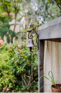 Detailed view of rustic cast iron doorbell featuring bird and leaf design on wood