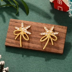 Detailed close-up of golden snowflake zircon earrings on a festive holiday background