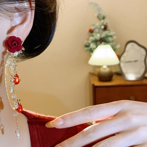 Close-up of red rose tassel earrings with gold chains and pearls for a festive look