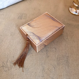 Detail of a rectangular fabric jewelry box with wave patterns and a brown tassel