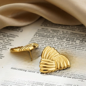 Macro shot of gold heart earrings with unique rippled texture and metallic luster