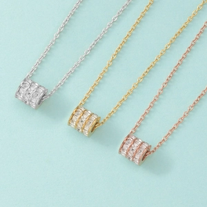 Close-up of triple cylinder pendants with pavé set white zircons in three metal colors