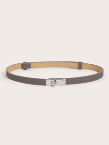 Detail of grey slim leather belt with silver rotating buckle and crosshatch texture