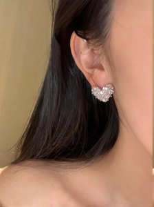Detailed view of silver heart earrings with micro-pave cubic zirconia on a model's ear