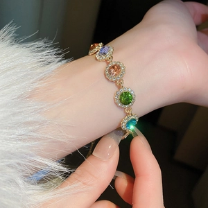 Bracelet vintage doré élégant avec pierres précieuses rondes colorées porté au poignet