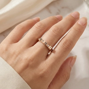 Dettaglio anello in acciaio oro rosa con numeri romani e cristalli scintillanti