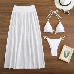 Flat lay of white 3-piece bikini set with sheer mesh skirt and gold ring details