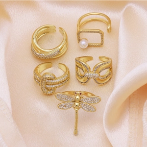 Set of five 18k gold plated adjustable rings with zircons and pearls on pink silk fabric