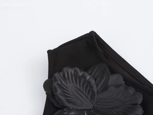 Dettaglio ravvicinato della decorazione floreale nera 3D su un vestito monospalla