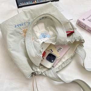 Detail of sage green canvas tote with sheep embroidery and functional drawstring closure