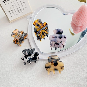 5-piece acetate claw clip set in marble and tortoise patterns on a stylish white leather base