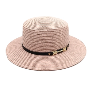 Détail du chapeau de paille rose avec ruban en cuir noir et boucle dorée pour l'été