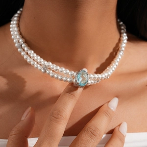 Detail of double-layer pearl necklace featuring a large oval blue gemstone pendant