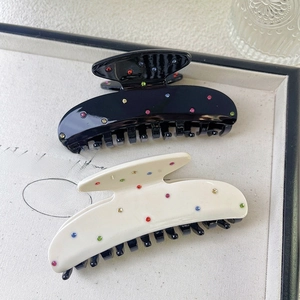 Elegant acetic acid hair claws in black and beige with colorful rhinestones on wood