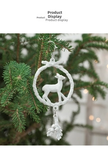 White reindeer resin pendant hanging on a green Christmas tree branch with bokeh background
