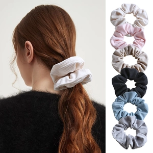 Detail of six waffle fabric scrunchies in various colors with model hairstyle view