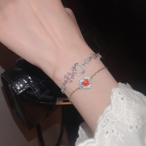Detailed view of silver bracelets with red zircon heart and cat profile charms