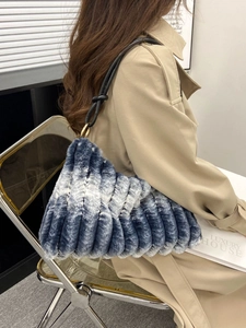 Blue and white gradient faux fur handbag with black leather strap on a model