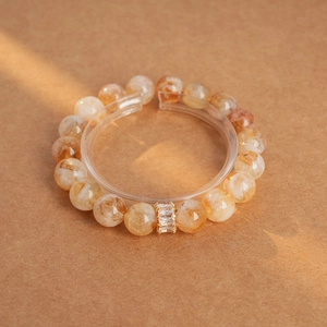 Handcrafted tiger eye and amethyst beaded bracelet with gold gemstone charm in warm light