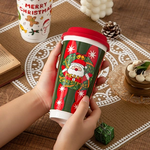 Green Santa Claus ceramic travel mug with red silicone lid on a festive wooden table
