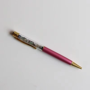 Detail of rose red metal ballpoint pen with crystal stones in clear barrel and gold trim