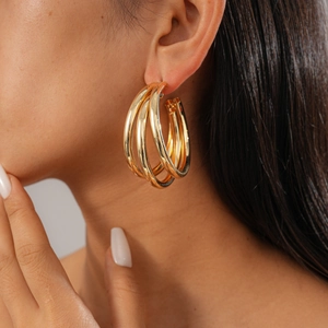 Detail of layered gold geometric triple hoop earrings worn by a model in close-up view