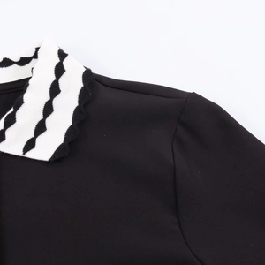 Détail du haut polo noir avec col en tricot à motifs ondulés noirs et blancs élégant