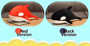 Detail of cute plush orca pillows in red and black colors on a wooden table
