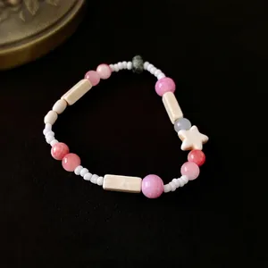 Handgemachtes Perlenarmband mit rosa Crackle-Perlen und Sternanhänger auf dunklem Stoff